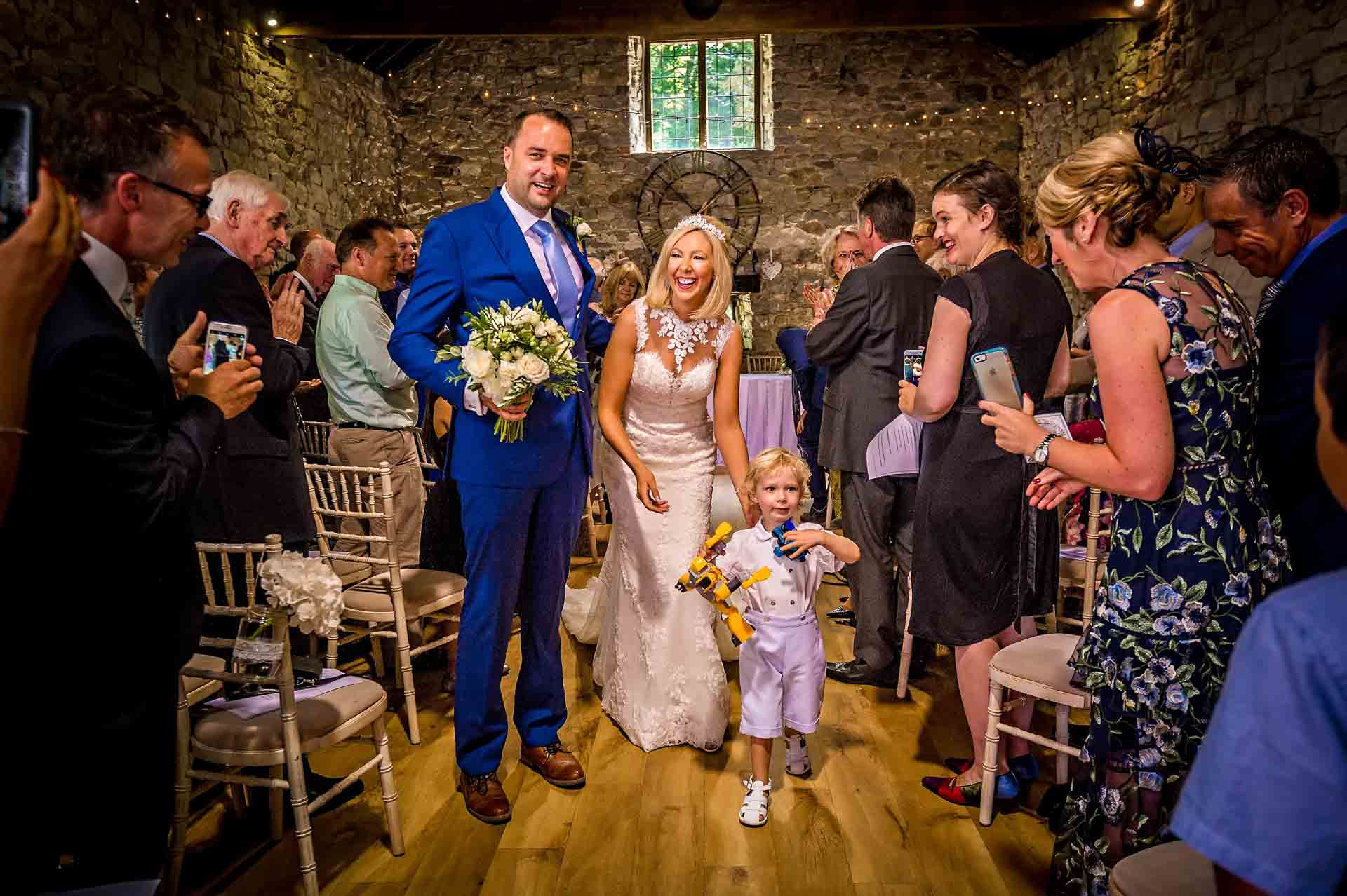 Pencoed House Wedding Photography - Bride and groom with Their Little Boy Walking Back Down Aisle Smiling